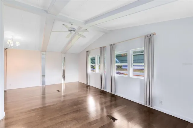 an empty room with wooden floor cabinet and windows