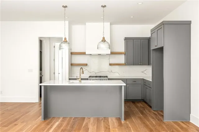 a kitchen with stainless steel appliances granite countertop a refrigerator a sink dishwasher a stove and a wooden floor