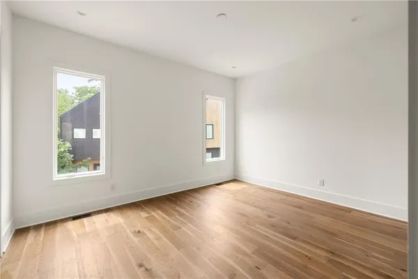 an empty room with wooden floor and windows