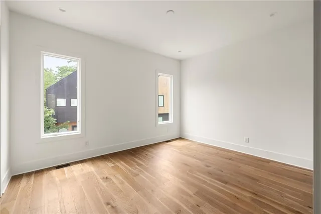 an empty room with wooden floor and windows
