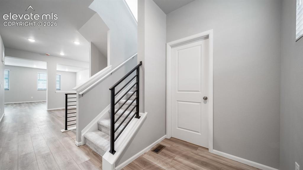 4896 Truscott Road Colorado Springs, CO 80925 - Photo 3 of 34 Modern staircase with black horizontal railing and white newel posts, paired with light gray wall tones and wood-finish flooringPhotos of a Model Home