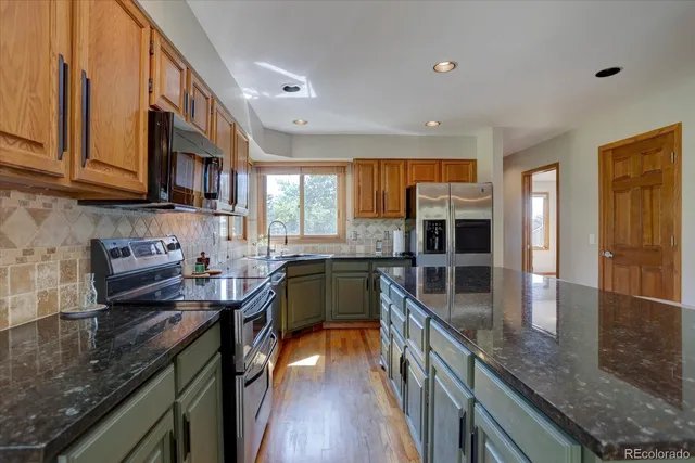 a kitchen with stainless steel appliances granite countertop a stove a sink and a microwave