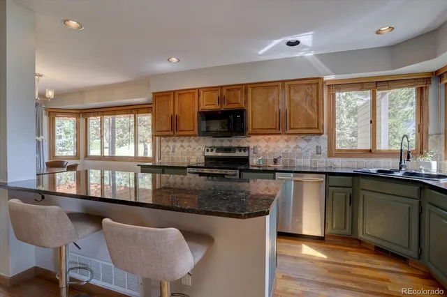a kitchen with granite countertop a stove a sink a window and dining table