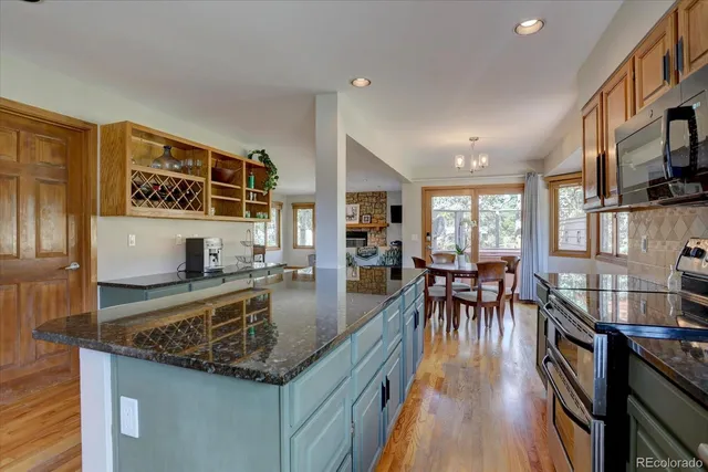 a kitchen with stainless steel appliances granite countertop a stove top oven a dining table and chairs with wooden floor