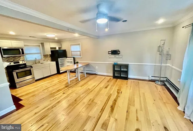 a living room with stainless steel appliances furniture and a kitchen view