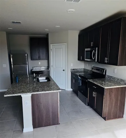 a kitchen with stainless steel appliances granite countertop a stove a sink and a microwave