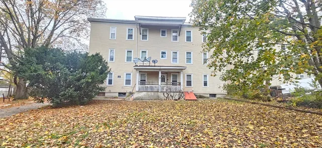 a front view of a house with garden and trees