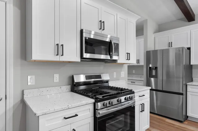 a kitchen with granite countertop white cabinets and stainless steel appliances