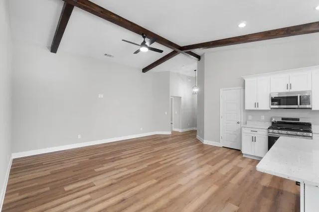 a view of a kitchen with wooden floor and stainless steel appliances