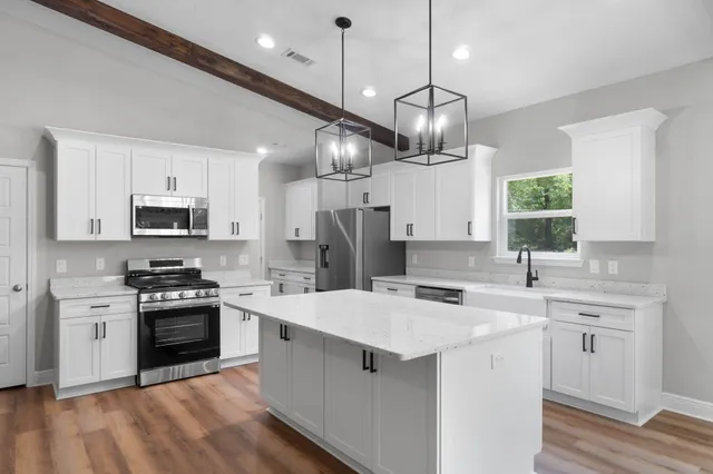 a kitchen with a sink stainless steel appliances a chandelier and cabinets