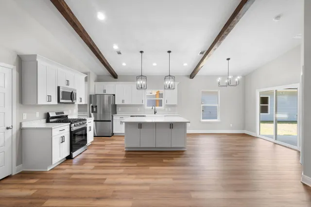 a large kitchen with cabinets wooden floor and stainless steel appliances