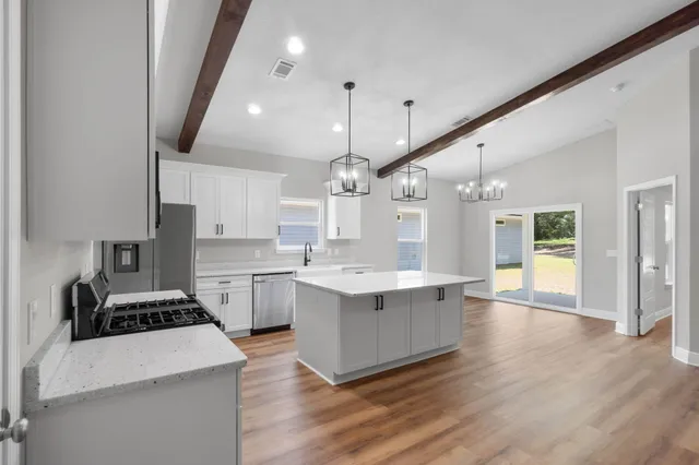 a large white kitchen with a stove a sink dishwasher and a refrigerator with wooden floor