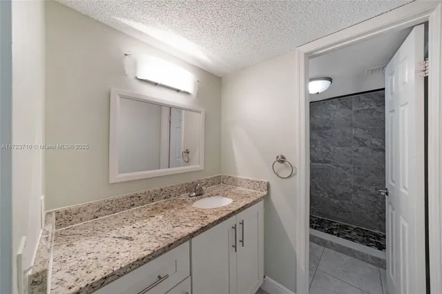 a bathroom with a granite countertop sink and a mirror
