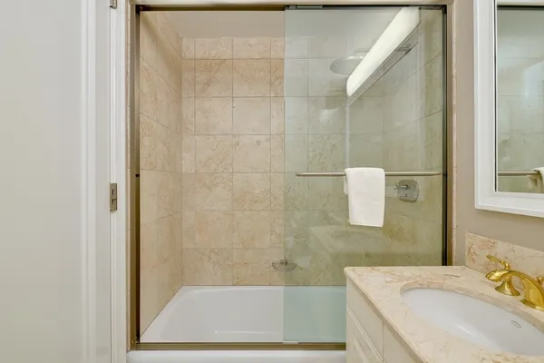 a bathroom with a granite countertop bathtub shower sink and mirror