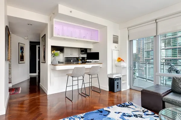 a kitchen with stainless steel appliances kitchen island granite countertop a refrigerator a stove top oven and a dining table with wooden floor