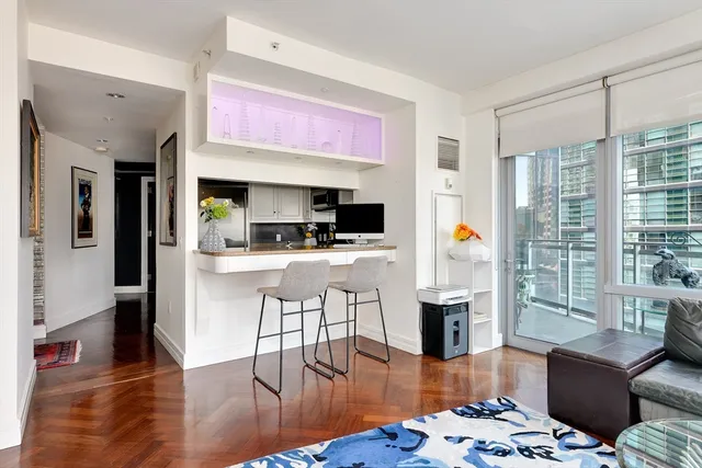 a kitchen with stainless steel appliances kitchen island granite countertop a refrigerator a stove top oven and a dining table with wooden floor