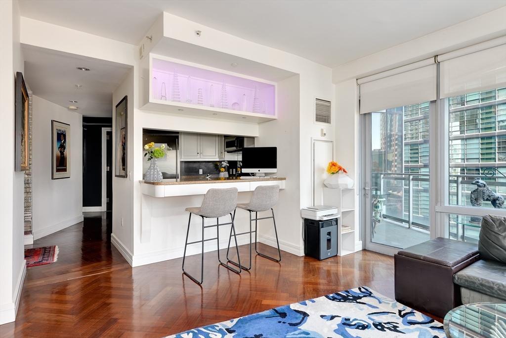 1 Avery Street, Unit 10D Boston, MA 02111 - Photo 5 of 21 a kitchen with stainless steel appliances kitchen island granite countertop a refrigerator a stove top oven and a dining table with wooden floor