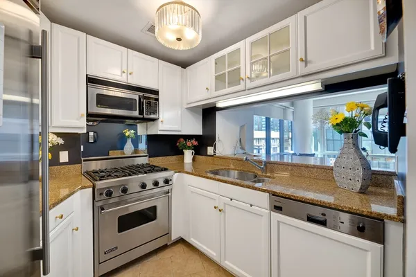 a kitchen with stainless steel appliances granite countertop a sink a stove and cabinets