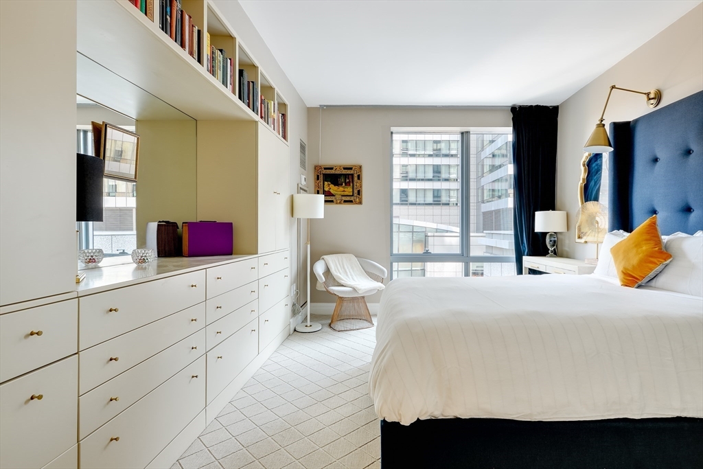 1 Avery Street, Unit 10D Boston, MA 02111 - Photo 10 of 21 a bedroom with a bed and dresser with mirror