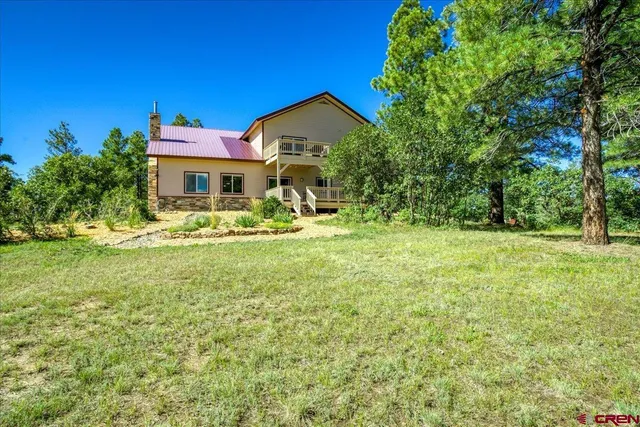 a view of an trees of a house with a yard