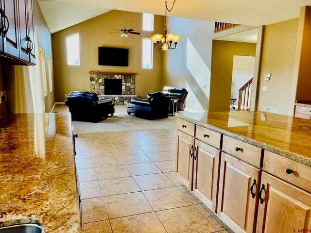 a living room with stainless steel appliances kitchen island granite countertop a sink and a black cabinets
