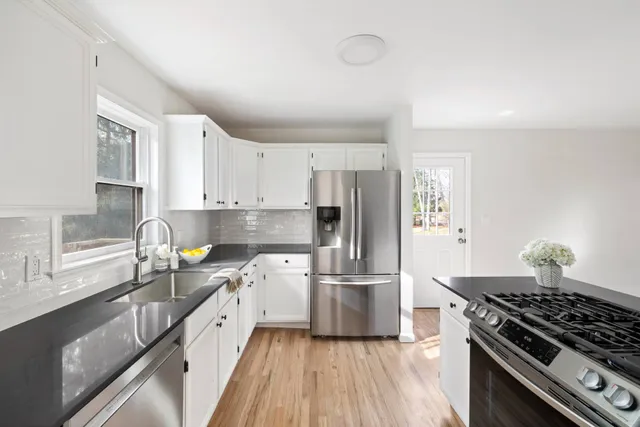a kitchen with granite countertop a refrigerator stove top oven and sink