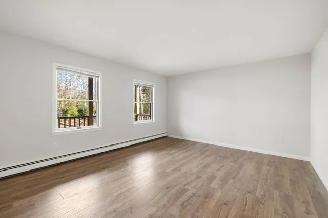 a view of an empty room with wooden floor and window