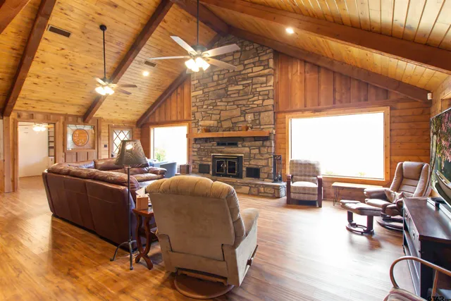 a living room with furniture a fireplace and a dining table with wooden floor