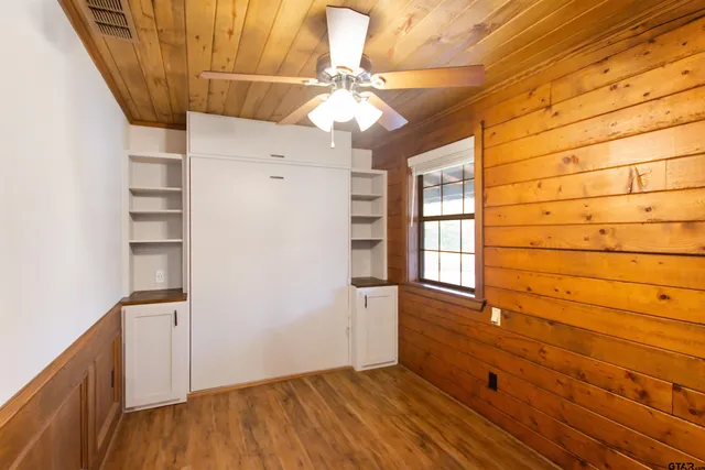 a view of empty room with wooden floor and fan