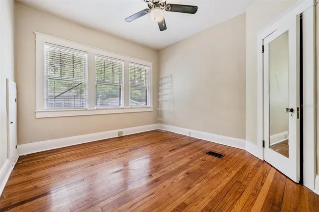 a view of empty room with wooden floor and fan