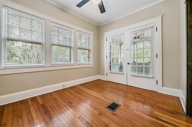 a view of an empty room with wooden floor and a window