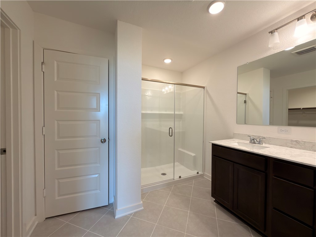 6053 Badger Street Bryan, TX 77807 - Photo 11 of 13 a bathroom with a glass door shower a sink and a mirror