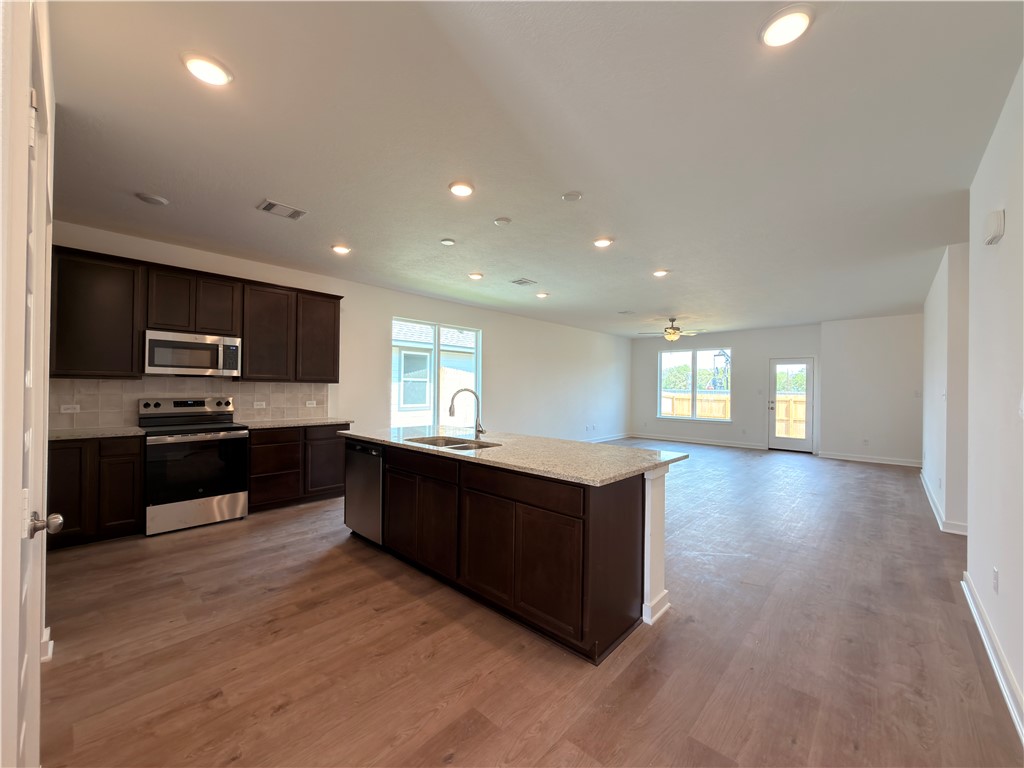 6053 Badger Street Bryan, TX 77807 - Photo 4 of 13 a kitchen with stainless steel appliances kitchen island granite countertop a stove a sink and a microwave