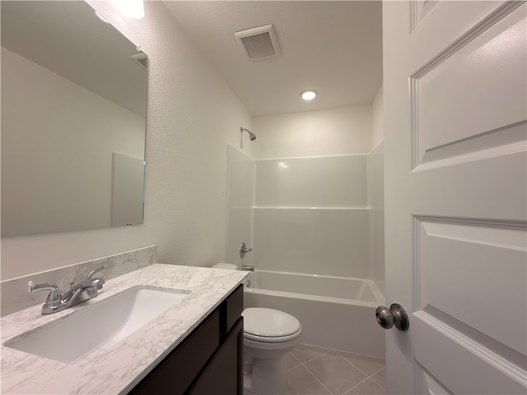6053 Badger Street Bryan, TX 77807 - Photo 8 of 13 a bathroom with a granite countertop sink a toilet and shower