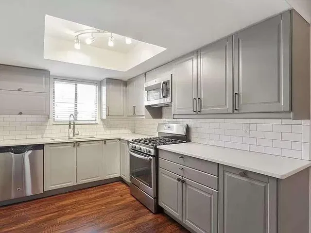a kitchen with a sink cabinets wooden floor and stainless steel appliances