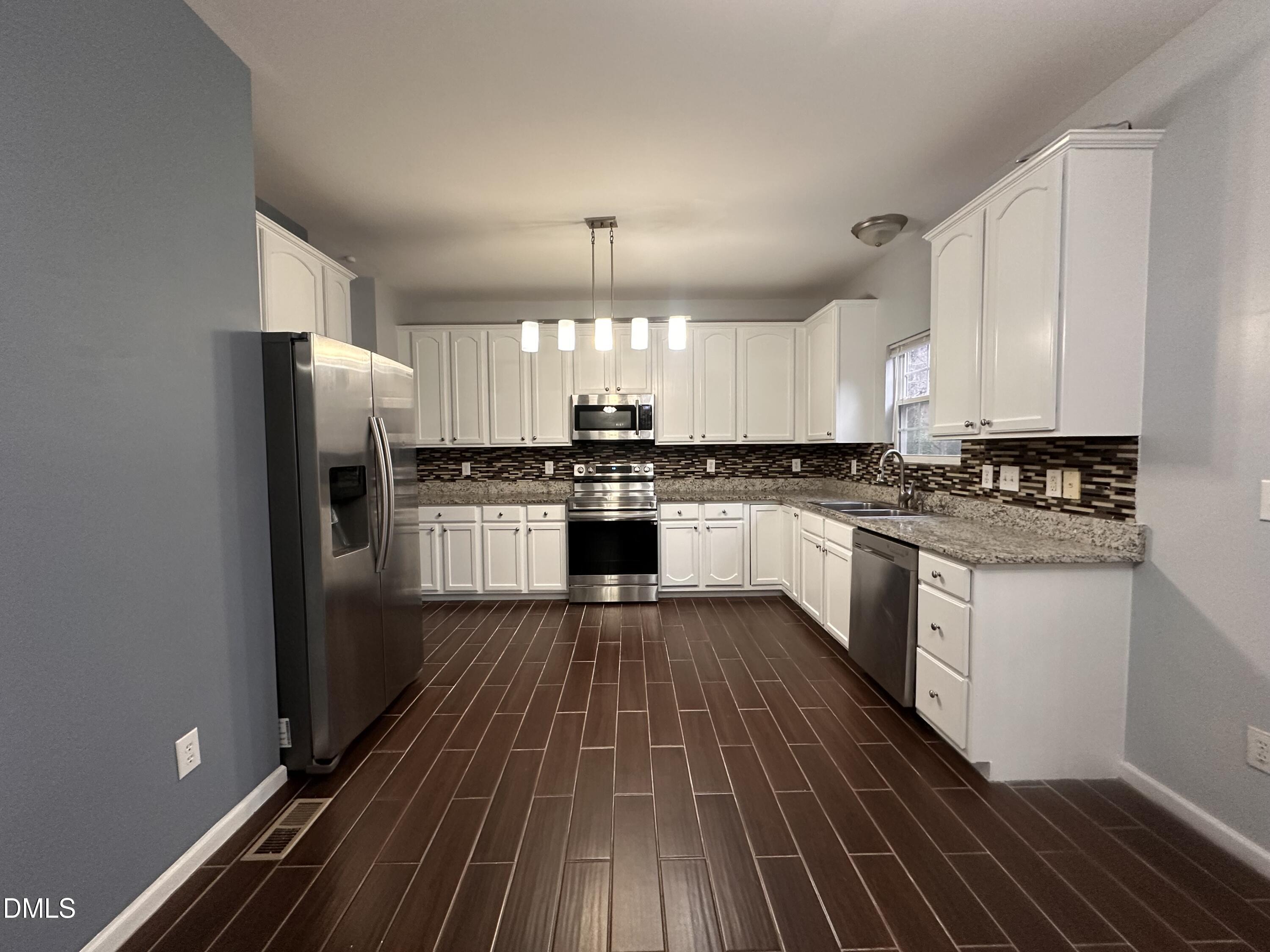 1220 Arbor Greene Drive Garner, NC 27529 - Photo 4 of 17 a kitchen with wooden floors appliances a sink and cabinets