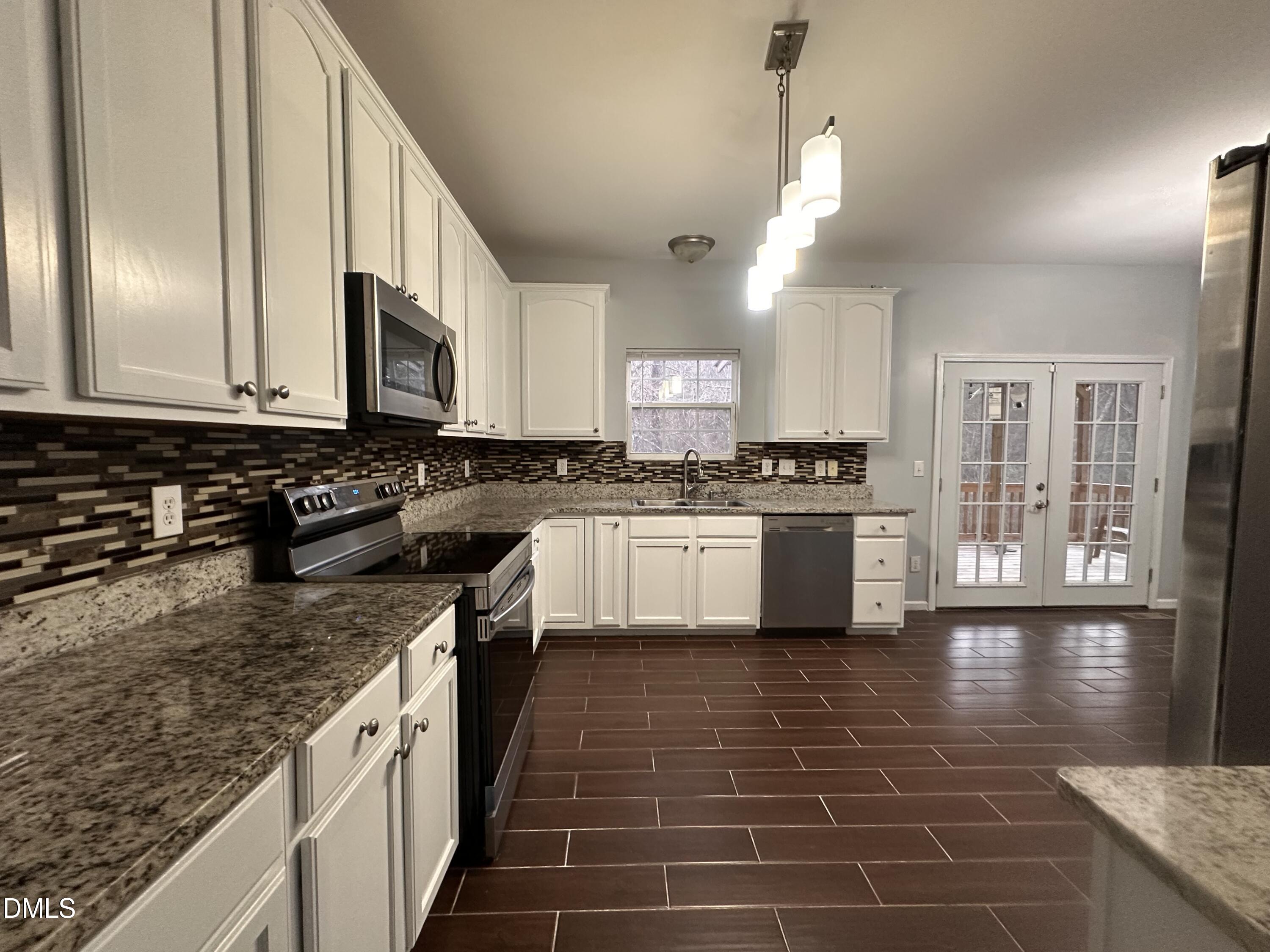 1220 Arbor Greene Drive Garner, NC 27529 - Photo 5 of 17 a kitchen with stainless steel appliances granite countertop a stove a sink and a microwave