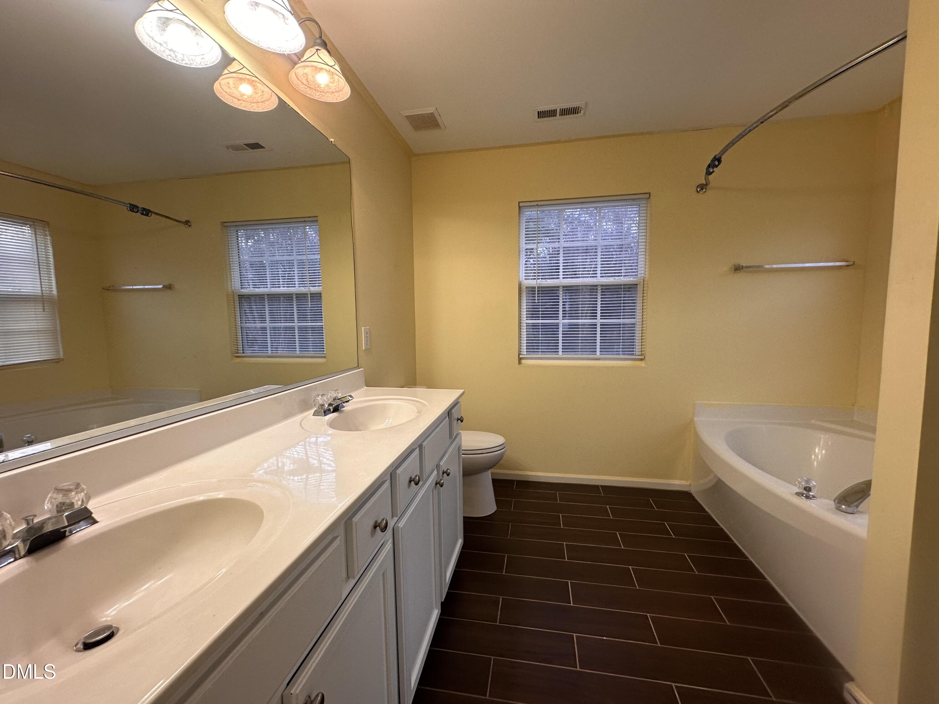 1220 Arbor Greene Drive Garner, NC 27529 - Photo 10 of 17 a bathroom with a double vanity sink a large mirror and a bathtub