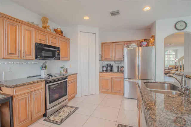 a kitchen with stainless steel appliances granite countertop a refrigerator stove top oven and sink