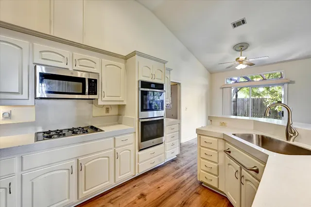 a kitchen with stainless steel appliances white cabinets and wooden floors