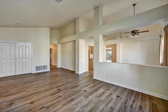 a view of an empty room with wooden floor and a window