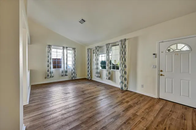 an empty room with wooden floor and windows