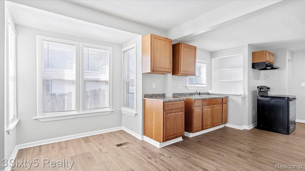 202 Haltiner Street River Rouge, MI 48218 - Photo 5 of 19 Kitchen with black electric range oven, a textured ceiling, light wood finished floors, wood finish cabinets, and light countertops