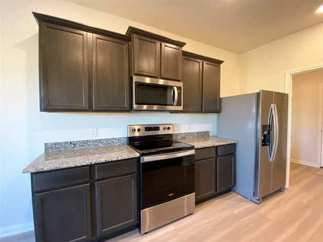 a kitchen with granite countertop wooden cabinets and stainless steel appliances