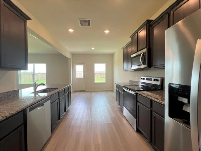 a kitchen with stainless steel appliances granite countertop hardwood floor sink stove dining table and chairs