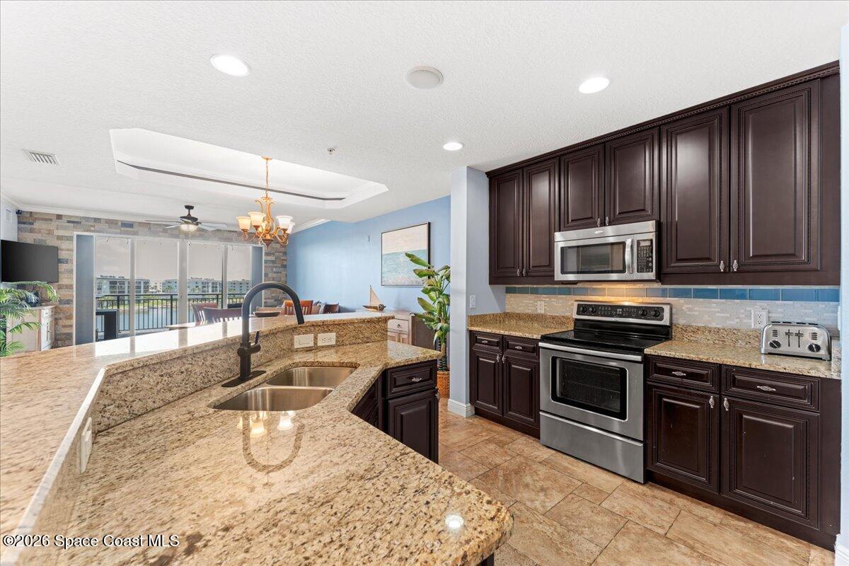 4125 West End Road, Unit 405 Cocoa Beach, FL 32931 - Photo 5 of 44 a kitchen with stainless steel appliances granite countertop a stove a sink and a microwave
