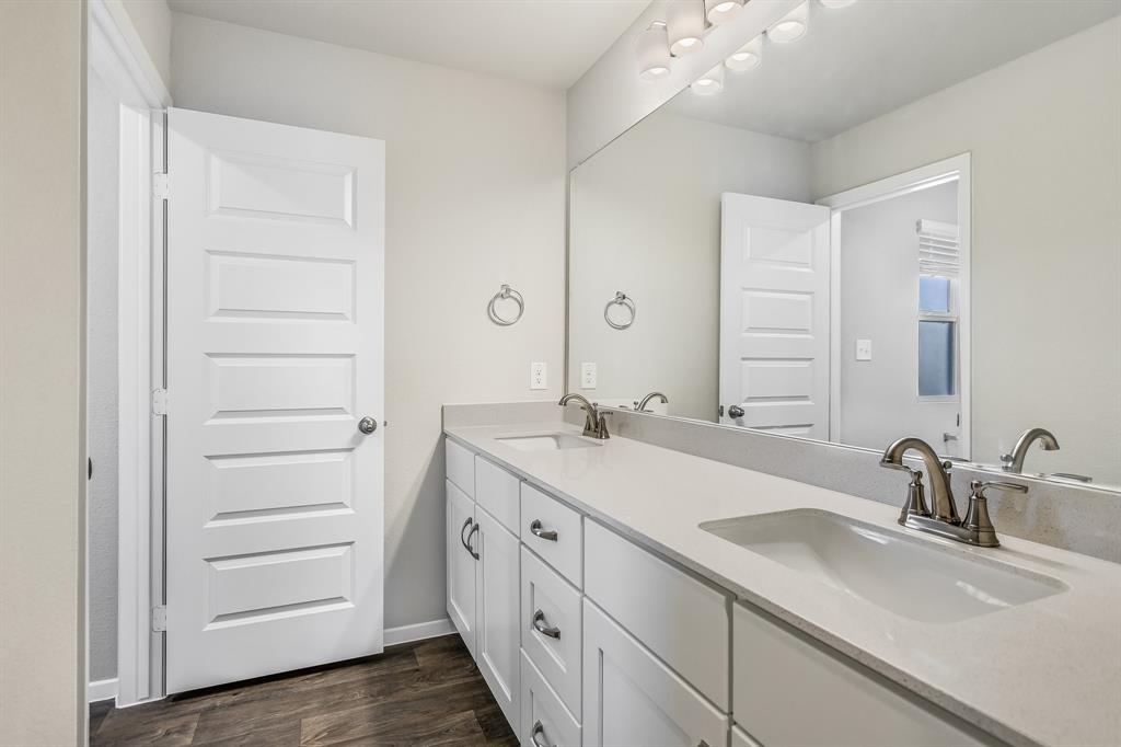 2808 Totley Road Manor, TX 78653 - Photo 16 of 21 Double vanity with white shaker-style cabinetry, light-toned countertops, two undermount sinks, and brushed nickel fixtures