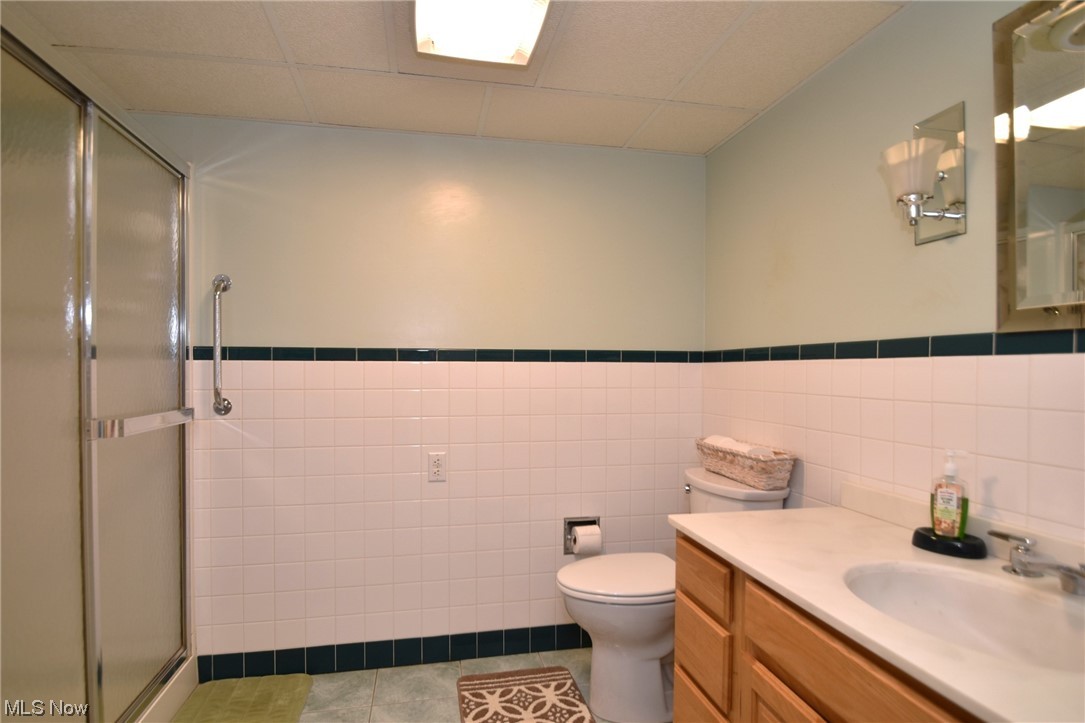28740 Forest Road Willowick, OH 44095 - Photo 22 of 27 Bathroom featuring tile floors, tile walls, a shower with door, vanity, and toilet