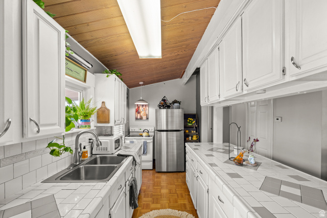 909 Rancho Boulevard Ogden, UT 84404 - Photo 8 of 27 Galley kitchen featuring white shaker cabinetry, stainless steel appliances, subway tile backsplash, and wood-finish countertops