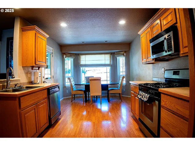a kitchen with stainless steel appliances granite countertop a stove a sink dishwasher and a microwave with wooden floor